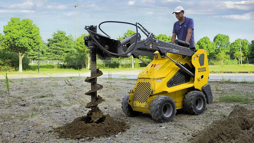Mini loader on wheels with auger in action